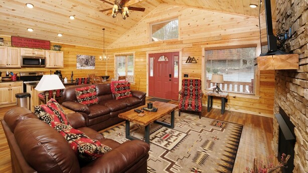 Ein gemütliches Blockhaus-Interieur mit Ledersofa, Couchtisch aus Holz und Kamin.