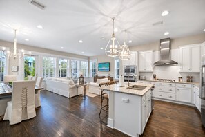 A spacious living area with a large island, white cabinetry, and a kitchen with modern appliances.