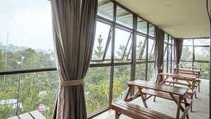 A room with large windows, wooden benches, and curtains. - Miracle Signature Hills (Ciater)