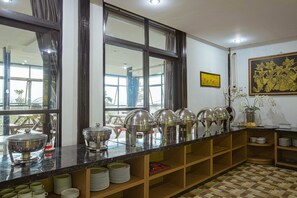 Disposição de buffet com várias estações de serviço, piso xadrez e uma grande janela com vista para o exterior.