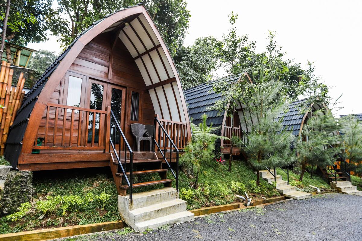 A wooden cabin with a curved roof, a balcony, and a staircase leading to the entrance.