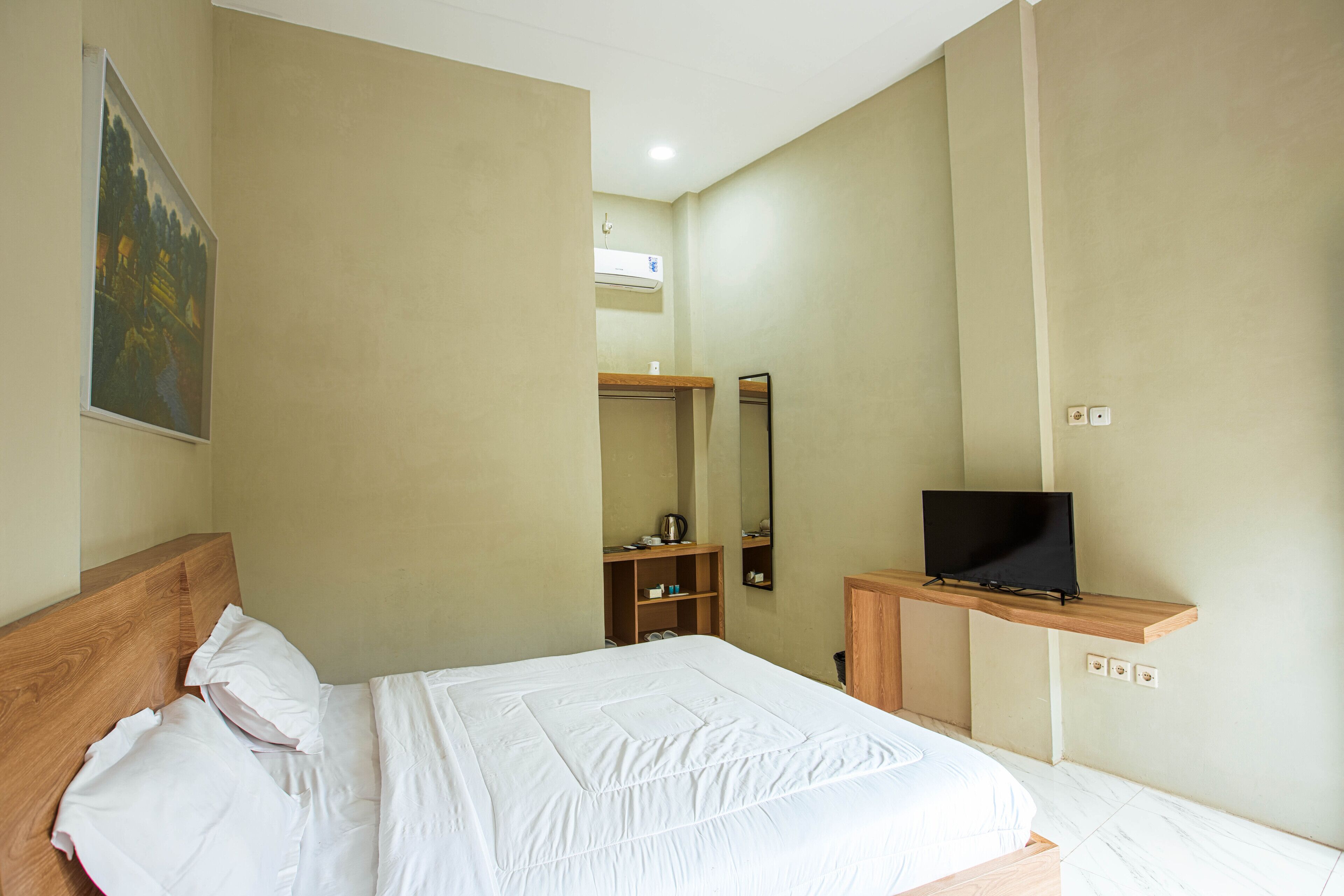 A hotel room with a bed, a television on a wooden stand, a mirror, and a painting on the wall.