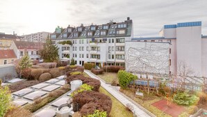 Ein Wohngebäude mit mehreren Balkonen, einem Dachgarten und moderner Architektur.