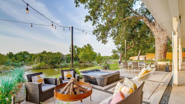 An outdoor patio with wicker furniture, a fire pit, and a hot tub. - Lakefront Retreat | Hot Tub + Kayaks | Sleeps 20 (Granbury)