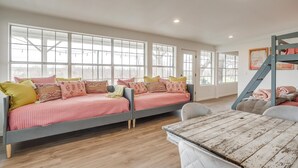 A spacious room with large windows, a bunk bed, a wooden table, and a staircase. - Lakefront Retreat | Hot Tub + Kayaks | Sleeps 20 (Granbury)