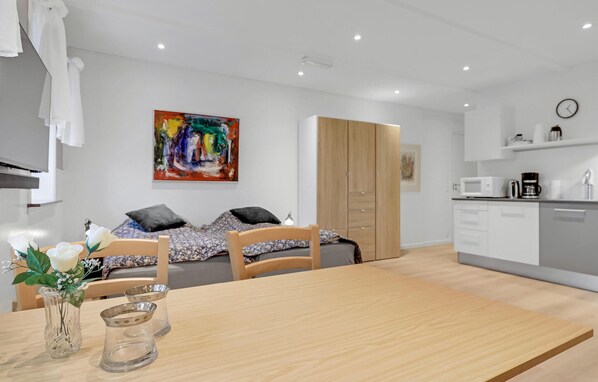 A modern, well-lit room with a bed, a dining table, and a kitchen area. - Stunning apartment in Nexø with WiFi (Nexø)