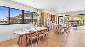 A modern kitchen with wooden cabinets, a stainless steel refrigerator, and a dining area with a round table and chairs.
