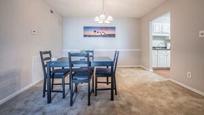 A dining area with a table and chairs, a ceiling light fixture, and a painting on the wall. - Cozy 2-Bedroom Suite Getaway (Sandy Springs)