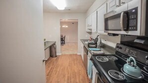 A compact kitchen with a microwave, stove, and cabinets. - Cozy 2-Bedroom Suite Getaway (Sandy Springs)