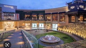 A shopping mall with a central courtyard, a fountain, and various stores including a visible 'Perimeter' store. - Cozy 2-Bedroom Suite Getaway (Sandy Springs)