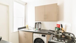 A compact kitchen with a washing machine, a stove, and a sink.