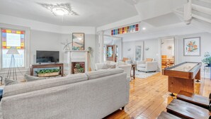 Un salón amplio con un sofá grande, una mesa de billar y una chimenea.