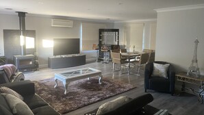 Una sala moderna con chimenea, televisor de pantalla plana, zona de comedor con mesa y sillas, y una reproducción decorativa de la Torre Eiffel.