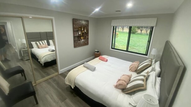 Un dormitorio moderno con una cama grande, un espejo, una ventana y vistas al exterior.