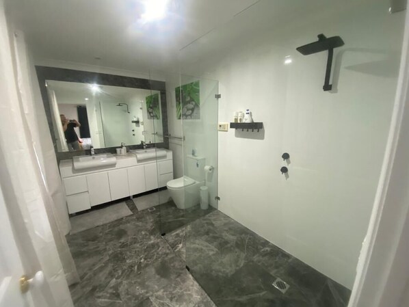 A modern bathroom with a glass shower enclosure, a white sink, and a toilet.