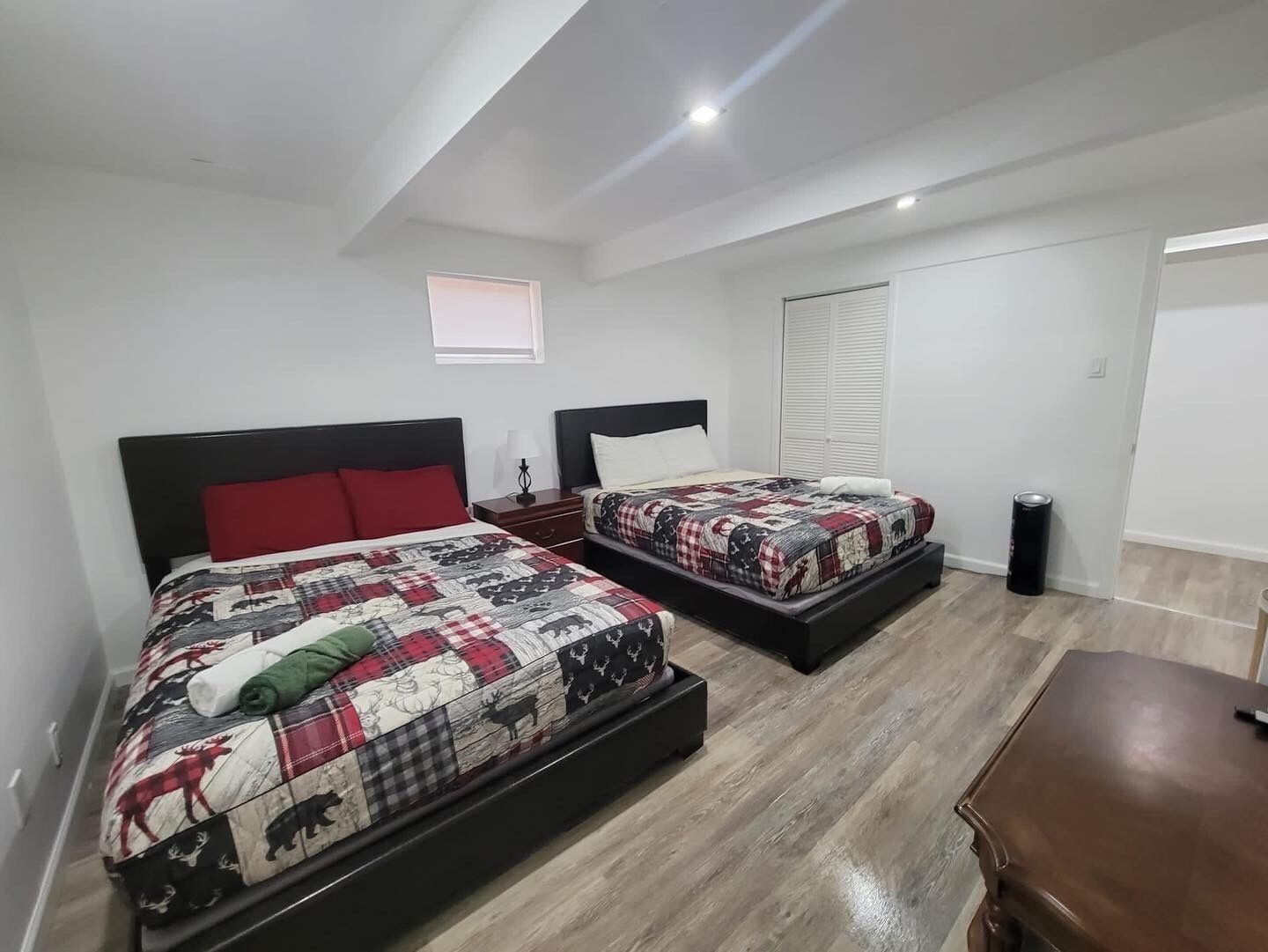 Une chambre à coucher avec deux lits, chacun étant agrémenté d’une couvre-lit matelassé, d’une table de chevet et d’une petite table d’appoint.