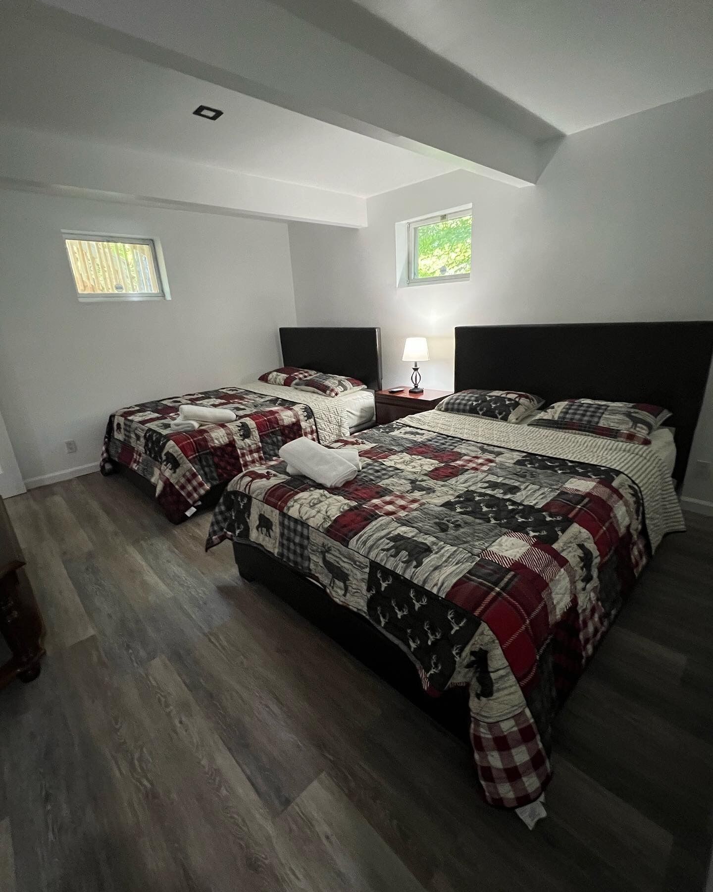 Een slaapkamer met twee bedden, een raam en een nachtkastje.