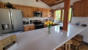 A modern kitchen with wooden cabinets, stainless steel appliances, and a white countertop. - Cabin for up to 10 People ! (Tobyhanna)