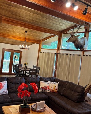 Relax in this stylish living room with a leather sofa, wooden coffee table, and a unique deer head on the wall.