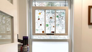 Una ventana con vistas a árboles, un limpiador de ventanas a la izquierda y una pared blanca.