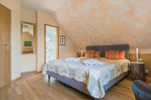 Un dormitorio con una cama grande, piso de madera, un espejo y techo con diseño texturizado.