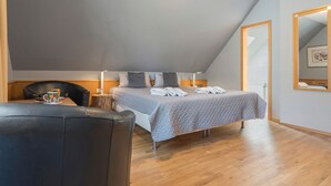 Ein Schlafzimmer mit Bett, Stuhl, Nachttisch und Spiegel.