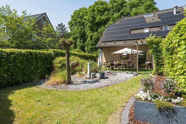 A house with a garden, a patio with outdoor furniture, and a solar panel roof.