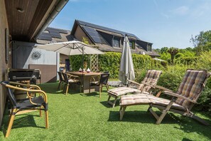 Un patio con mesa, sillas y zona de barbacoa.