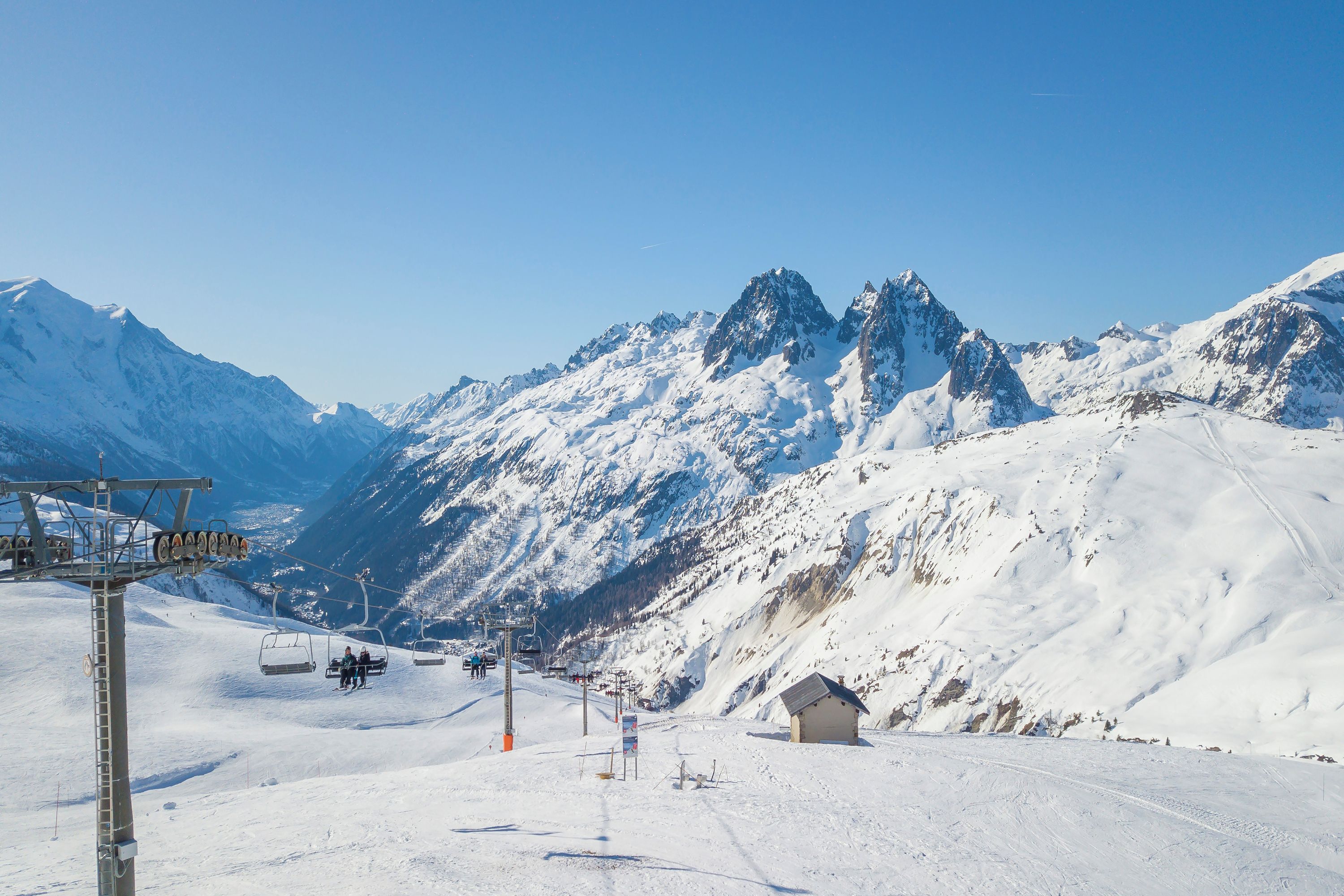 A snow-covered mountain with a ski lift and a small building.