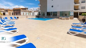 Ett poolområde på taket med blå solstolar och en swimmingpool.