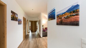 A hallway with wooden flooring, white walls, and framed landscape paintings. - Ferienwohnung Nummer 2 im Zweiten Stock (Übersee)