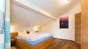 A bedroom with a wooden bed, a nightstand, a wall-mounted lamp, and a painting on the wall. - Ferienwohnung Nummer 2 im Zweiten Stock (Übersee)