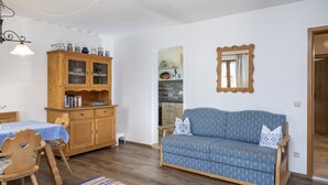 Ein gemütliches Wohnzimmer mit einem blau gemusterten Sofa, einer Holzkabine und einem Esstisch.