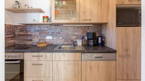 Eine moderne Küche mit Holzausziehtüren, einer Stein-Spritzschutzleiste, einer Edelstahl-Spüle und einem eingebauten Geschirrspüler.