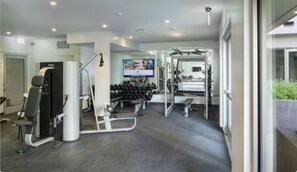 Work out in style with a fully equipped gym featuring a bench press, dumbbells, and cable machine.