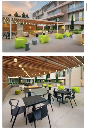 Relax in the contemporary lounge area with curved sofas, round tables, and black chairs under a pergola with hanging lights.