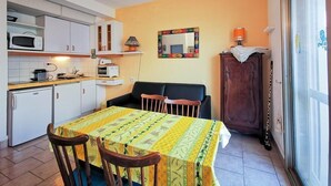A compact kitchen with white cabinets, a microwave, and a toaster. There is a dining table with a yellow tablecloth and two chairs. A cabinet with a leopard print towel is visible, and a mirror hangs on the wall. - Le Lavandou, Cabin studio to rent for 4 people, sea view, direct access to the beach (LE LAVANDOU)