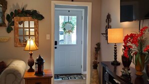 A cozy living room with a wooden coffee table, a lamp, a fireplace, and a television mounted on the wall. - Comfortable and relaxing Cottage getaway. (Saint Marys)