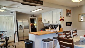 A modern kitchen with white cabinets, a wooden island, and bar stools. - Comfortable and relaxing Cottage getaway. (Saint Marys)