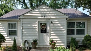 A single-story house with a front door, number 706, and a small porch area with potted plants. - Comfortable and relaxing Cottage getaway. (Saint Marys)