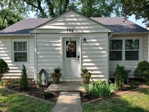 A single-story house with a front door, number 706, and a small porch area with potted plants. - Comfortable and relaxing Cottage getaway. (Saint Marys)