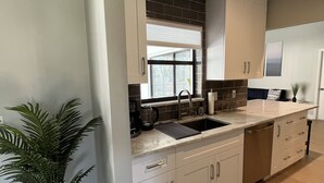 A modern kitchen with white cabinets, a black backsplash, and a large window. - Home in Englewood / heated pool (Englewood)