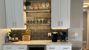 A modern kitchen with white cabinetry, a built-in wine rack, and a dishwasher. - Home in Englewood / heated pool (Englewood)