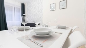 Una mesa de comedor dispuesta con platos, vasos y cubiertos, con un mantel individual que muestra iconos.