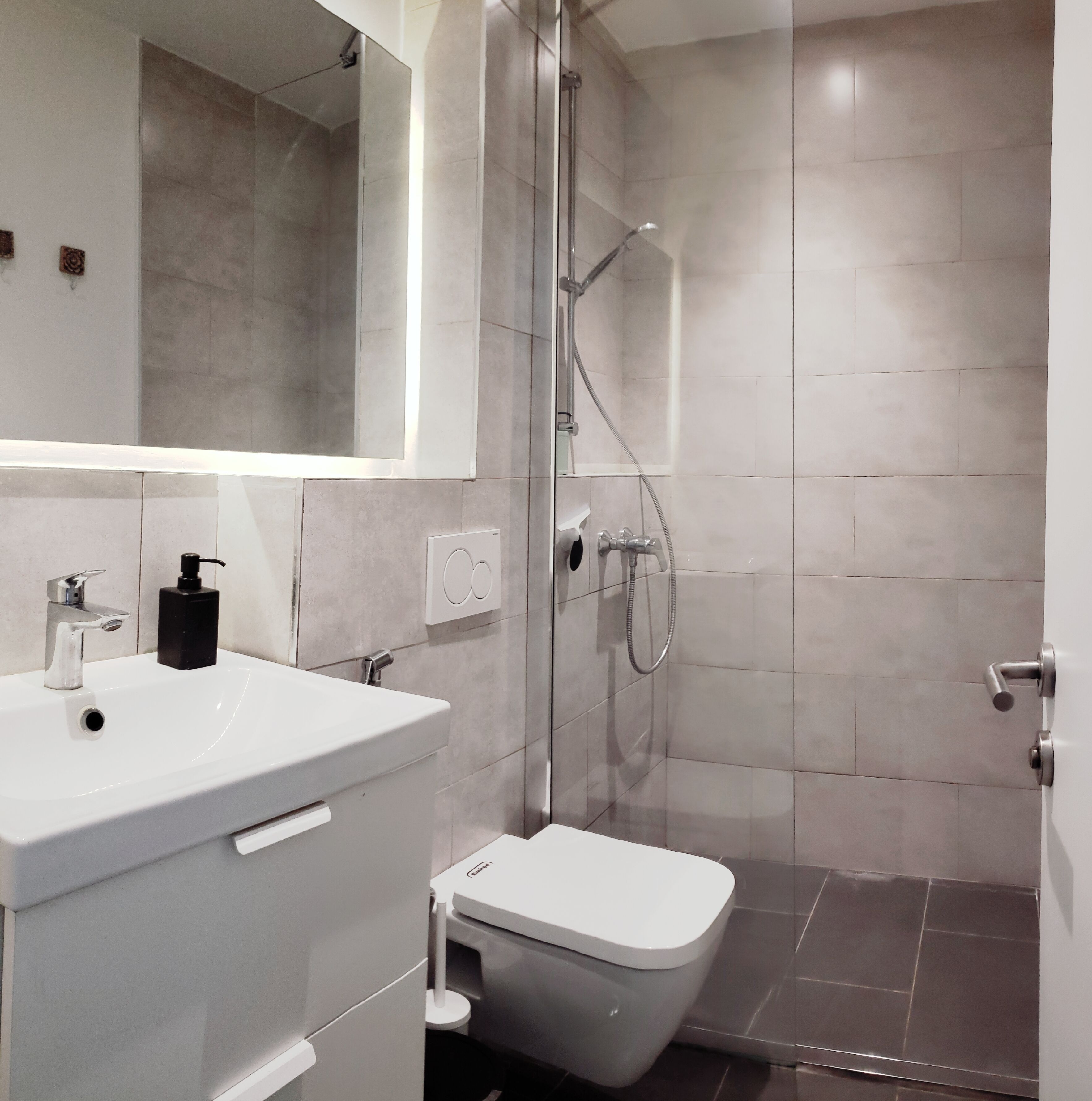 Une salle de bain moderne avec un lavabo blanc, des toilettes et une douche à parois de verre.