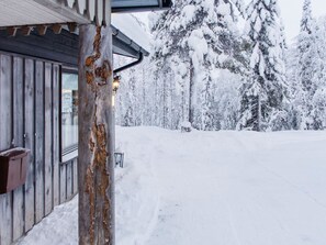 Una cabana de fusta amb un paisatge cobert de neu i arbres al fons.