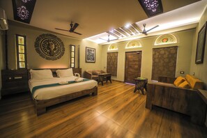 A hotel room with a bed, a seating area, a desk, and a door. - Breathing Earth (Diamond Harbour)