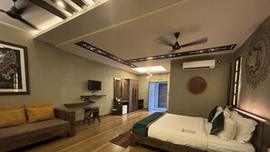 A bedroom with a bed, a sofa, a TV, and a ceiling fan. - Breathing Earth (Diamond Harbour)