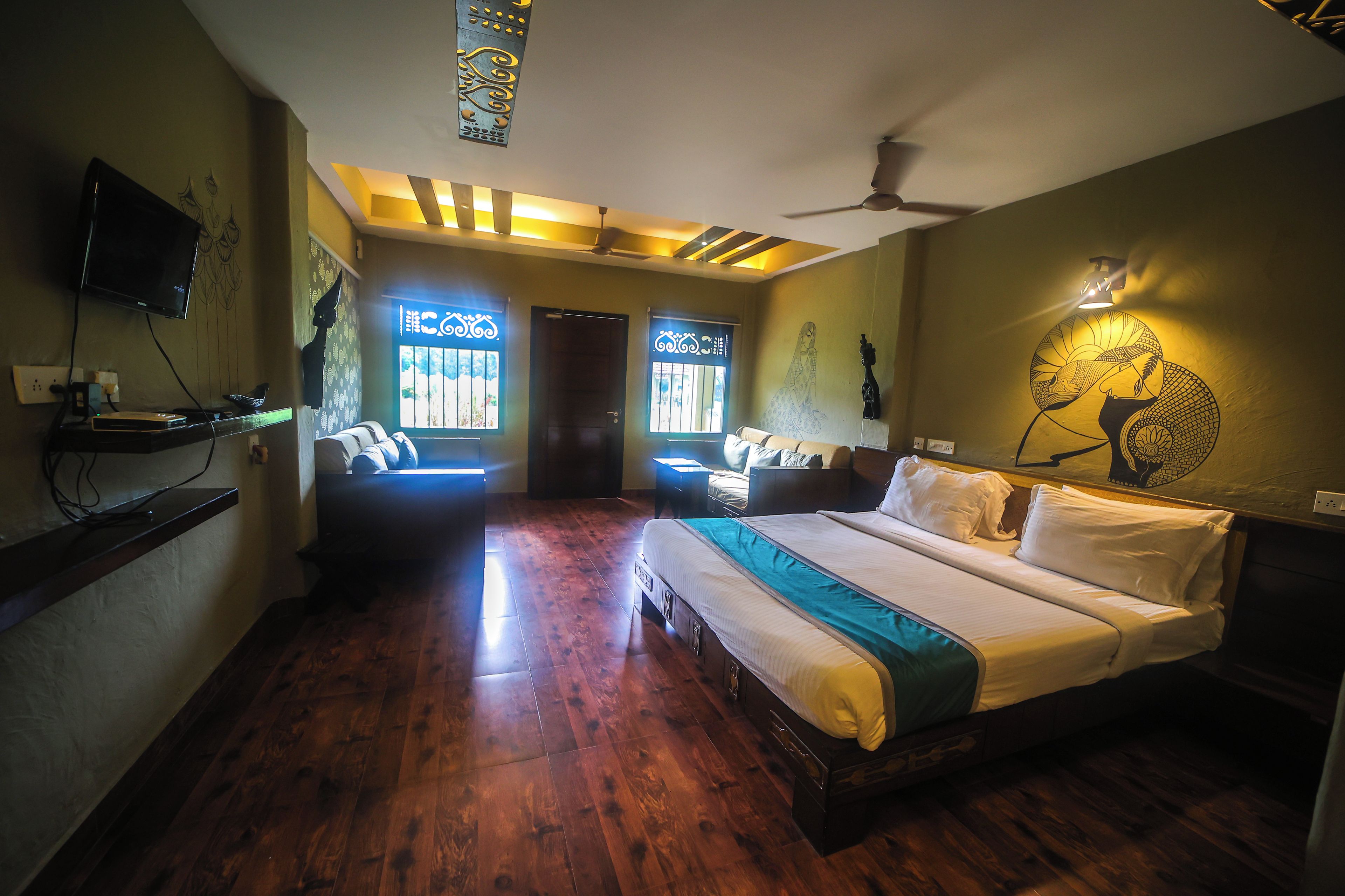 A hotel room with a large bed, a ceiling fan, and a wall-mounted TV.