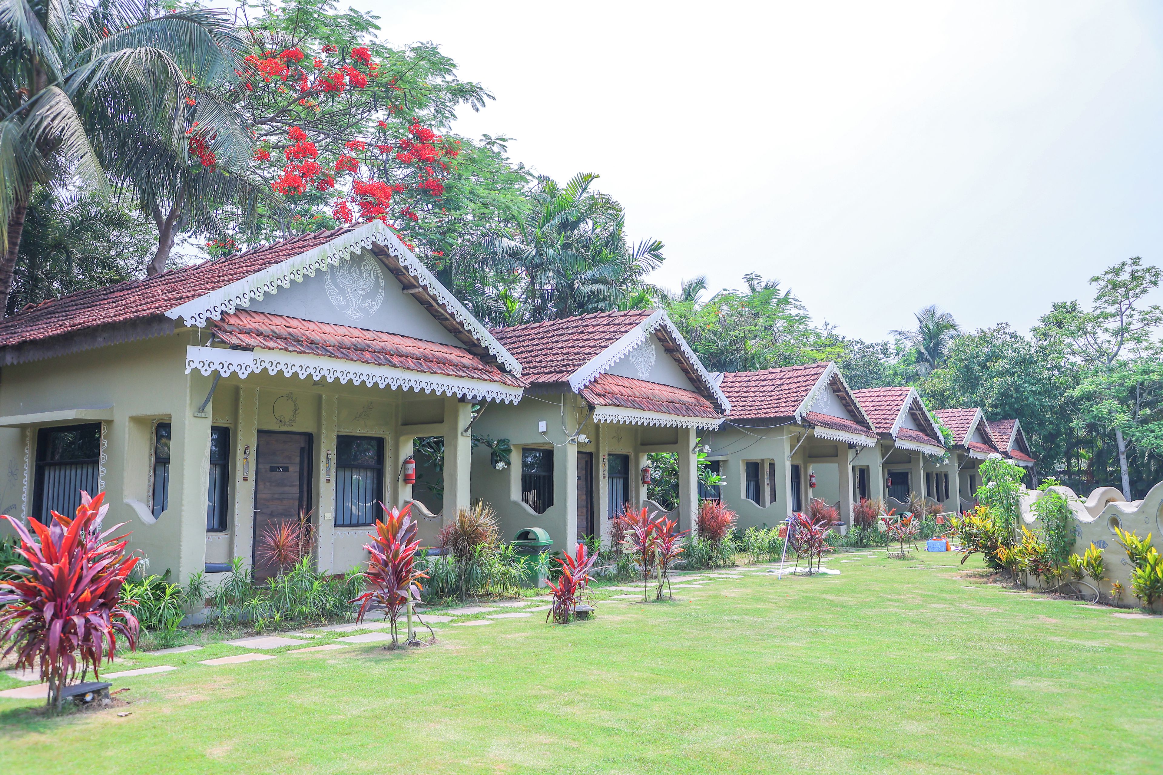 A row of traditional-style villas with tiled roofs, surrounded by well-maintained lawns and tropical plants.